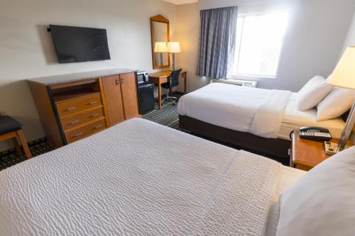 a hotel room with two beds and a flat screen tv at Days Inn by Wyndham Florence Cincinnati Area in Florence