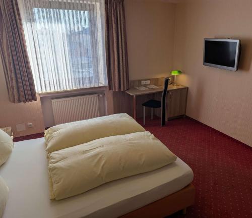 a hotel room with a bed and a desk at Stadthotel Augsburg in Augsburg