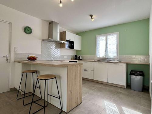 une cuisine avec des murs verts, un comptoir et des tabourets dans l'établissement Maison 3 pièces 4 couchages Dolus d'Oléron DDO000-403, à Dolus-d'Oléron