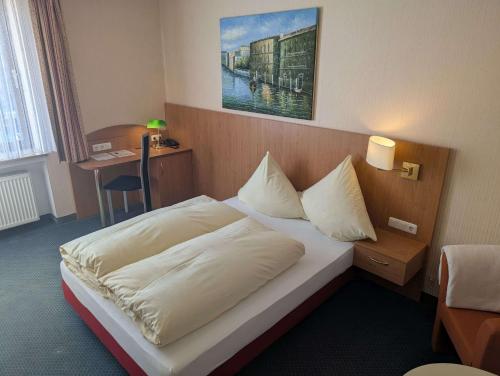 a hotel room with a bed and a desk at Stadthotel Augsburg in Augsburg