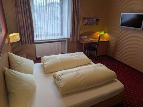 a hotel room with two white pillows on a bed at Stadthotel Augsburg in Augsburg
