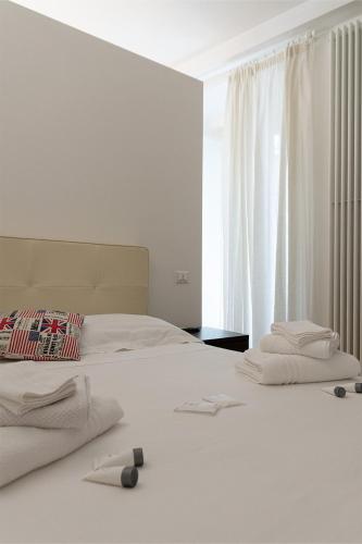 1 dormitorio con 2 camas con sábanas blancas y ventana en Graffiti Living Niglio, en Corato