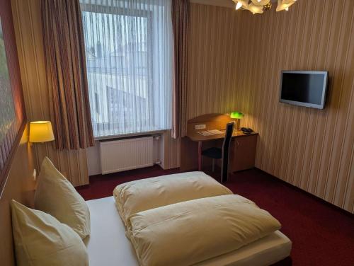 a hotel room with a bed and a desk and a television at Stadthotel Augsburg in Augsburg