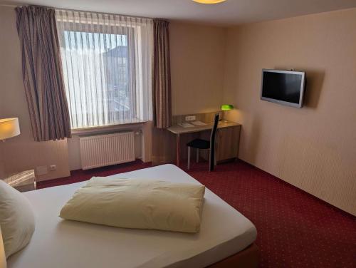 a hotel room with a bed and a desk and a television at Stadthotel Augsburg in Augsburg