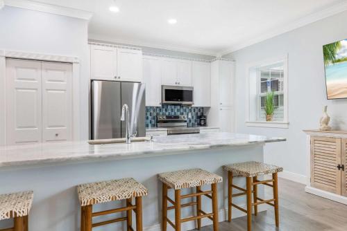 a kitchen with white cabinets and a counter with stools at Cozy Studio Condo in Sebastian in Sebastian