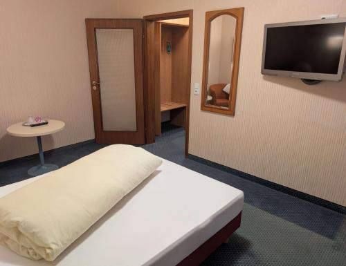 a room with a bed and a tv on a wall at Stadthotel Augsburg in Augsburg
