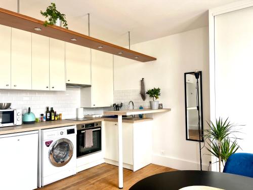 La cuisine est équipée de placards blancs et d'un lave-vaisselle. dans l'établissement Eiffel Tower - Cosy Studio, à Paris