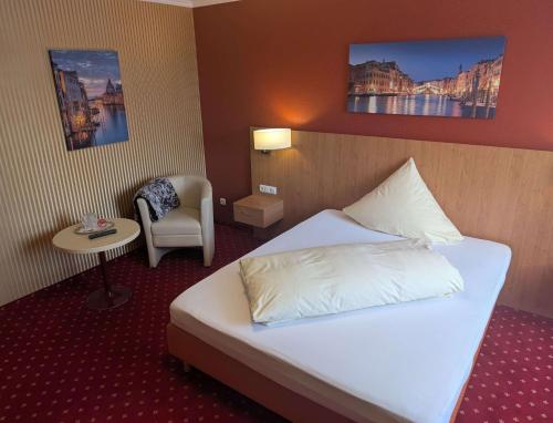 a hotel room with a bed and a chair at Stadthotel Augsburg in Augsburg