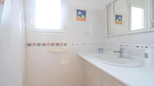une salle de bain blanche avec un lavabo et un miroir dans l'établissement La Lamparo n202 - 2P4, au Cap d'Agde