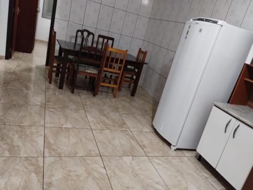 a kitchen with a table and a white refrigerator at Apartamento superior 04 quartos in Torres