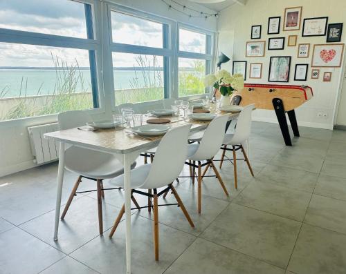 - une salle à manger avec une table, des chaises et un piano dans l'établissement Maison pieds dans l'eau d'exception en Bretagne !, à Plérin
