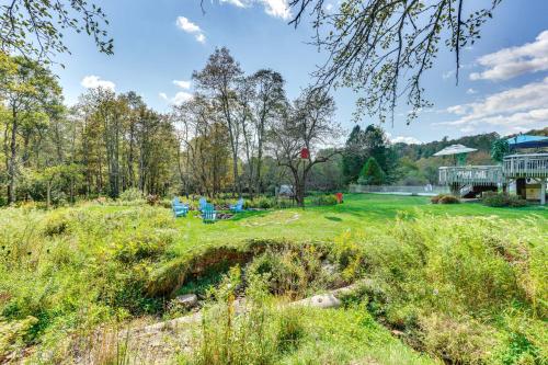 a field with chairs and a house in the background at Peaceful 1-Acre Parksville Home Large Deck and Yard in Parksville