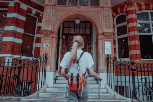 a woman with a red backpack standing in front of a building at Astor Hyde Park Hostel in London