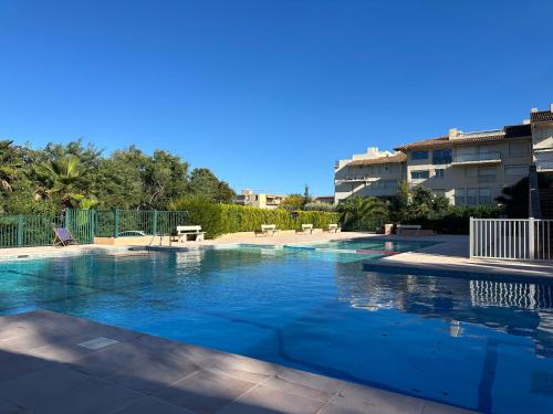 Una piscina con agua azul frente a un edificio. en Saint-Tropez - Studio 40 m2, en Saint-Tropez