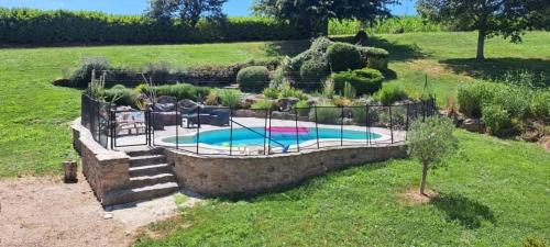 a backyard with a swimming pool and a stone wall at Villa spacieuse avec piscine à Bas-Ségala in La Bastide-lʼÉvêque