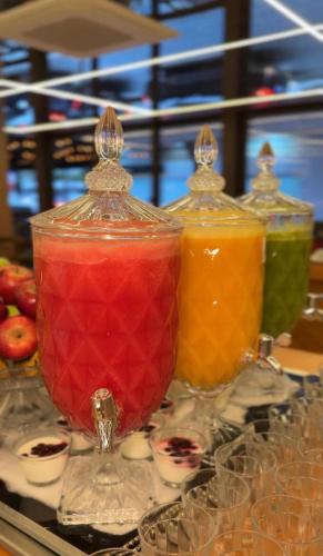 a group of four glass vases with different colored liquids at Apê Av Paulista Haddock Lobo in Sao Paulo