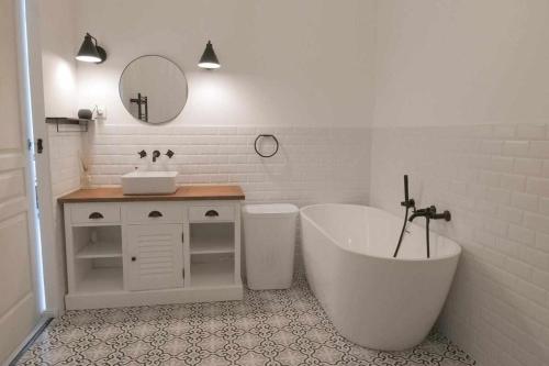 une salle de bain blanche avec une baignoire et un lavabo dans l'établissement Villa Gozforn - Piscine et plage à pied, à Fouesnant