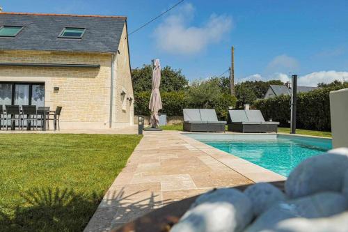 une piscine avec deux chaises et un parasol à côté d'une maison dans l'établissement Villa Gozforn - Piscine et plage à pied, à Fouesnant