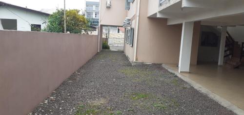 an empty alley next to a building with a fence at Apartamento 01 quarto superior in Torres