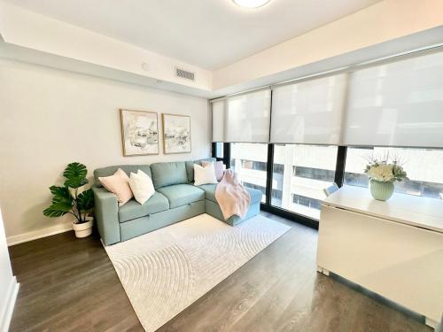 a living room with a blue couch and a large window at Condo in Yorkville - Newly Furnished Luxury Unit in Toronto