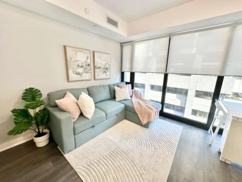 a living room with a blue couch and windows at Condo in Yorkville - Newly Furnished Luxury Unit in Toronto