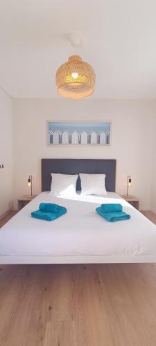 - un grand lit blanc avec 2 oreillers bleus dans l'établissement Heron- Maison avec jacuzzi privatif 4pers, à Les Sables-dʼOlonne