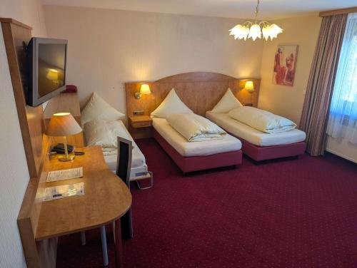 a hotel room with two beds and a table at Stadthotel Augsburg in Augsburg