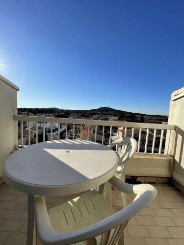 d'une table blanche et de deux chaises sur un balcon. dans l'établissement Studio Port Soleil PS604 - 2 personnes accès Piscine, au Cap d'Agde
