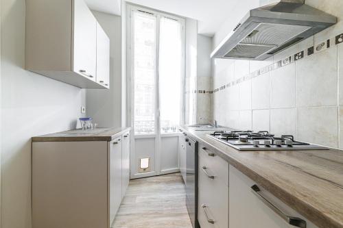 une cuisine avec des armoires blanches et un four à plaques de cuisson dans l'établissement L'Escapade Cannoise Forville, à Cannes