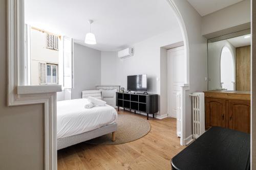 une chambre blanche avec un lit et une cuisine dans l'établissement L'Escapade Cannoise Forville, à Cannes