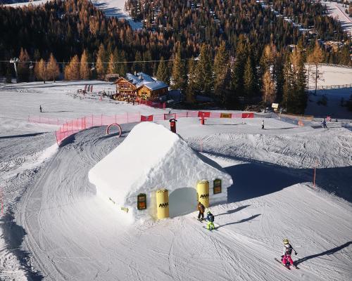 un grupo de personas en una pista de esquí con una rampa de nieve en Hotel Pordoi Passo Pordoi Vegetarian Hotel, en Canazei