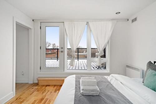 a white bedroom with a large window and a bed at 3 bedroom Penthouse Great for family vacation in Montréal