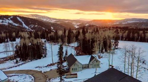 a house in the snow with the sunset in the background at BRAND NEW World Adventure at Aspen Crest in Beaver