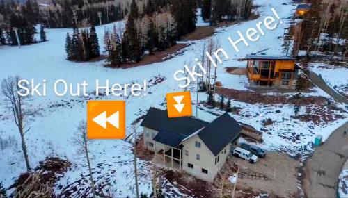 a house in the snow with the words ski out here at BRAND NEW World Adventure at Aspen Crest in Beaver
