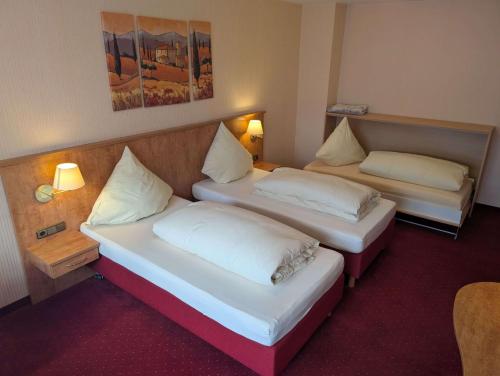 two beds in a hotel room with two lamps at Stadthotel Augsburg in Augsburg