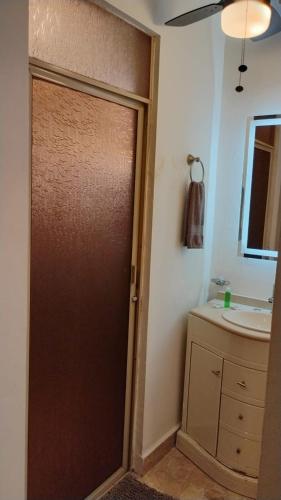 a bathroom with a brown door next to a sink at Cumbresuites in Monterrey