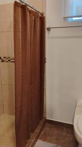 a bathroom with a shower with a brown shower curtain at Cumbresuites in Monterrey