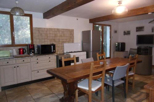 une cuisine avec une table en bois avec des chaises et un réfrigérateur dans l'établissement DOMAINE LE PLA de LIÉRE, à Maury