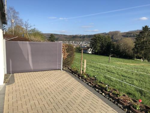 a white privacy fence with a field in the background at Ferienwohnung Wiesenblick in Plettenberg