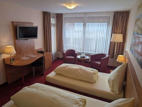 a hotel room with a bed and a desk and a television at Stadthotel Augsburg in Augsburg