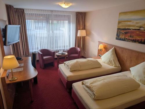 a hotel room with two beds and a television at Stadthotel Augsburg in Augsburg