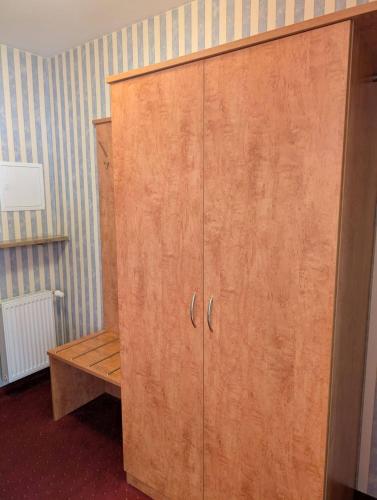 a wooden cabinet in a room with a bench at Stadthotel Augsburg in Augsburg