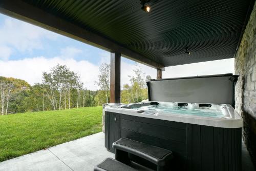 patio con vasca idromassaggio e vista su un campo di Sommet White Golf Hot tub Ski 10min a Saint-Faustin