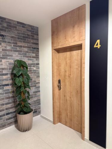 a wooden door with a plant next to a brick wall at LAMBERT Residences in Lučenec