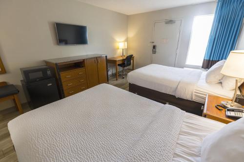 a hotel room with two beds and a television at Days Inn by Wyndham Florence Cincinnati Area in Florence