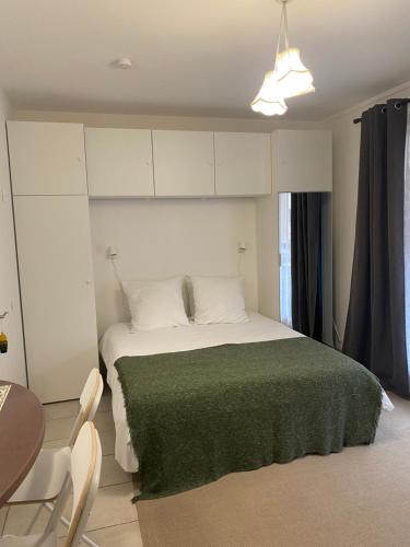 une chambre avec un grand lit avec une couverture verte dans l'établissement Annecy centre, charmant studio, à Annecy