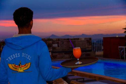 a person holding a tray with a drink at Thebes Hotel in Luxor