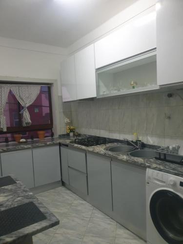 a kitchen with white cabinets and a sink and a dishwasher at De Pina Apartments in Pedra Badejo