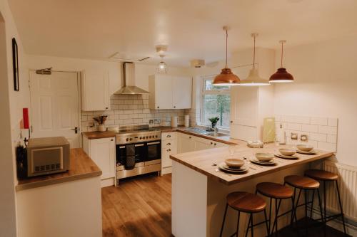 a kitchen with white cabinets and a island with bar stools at 6-BR - Perfect for Contractors - Long-stay Savings in Sheffield