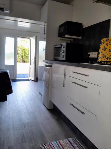 a kitchen with white cabinets and a microwave at Appartement Meublé bord de mer FOS SUR MER in Fos-sur-Mer